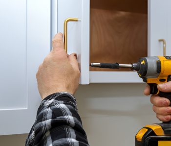 close-up of a man installing a kitchen cabinet handle