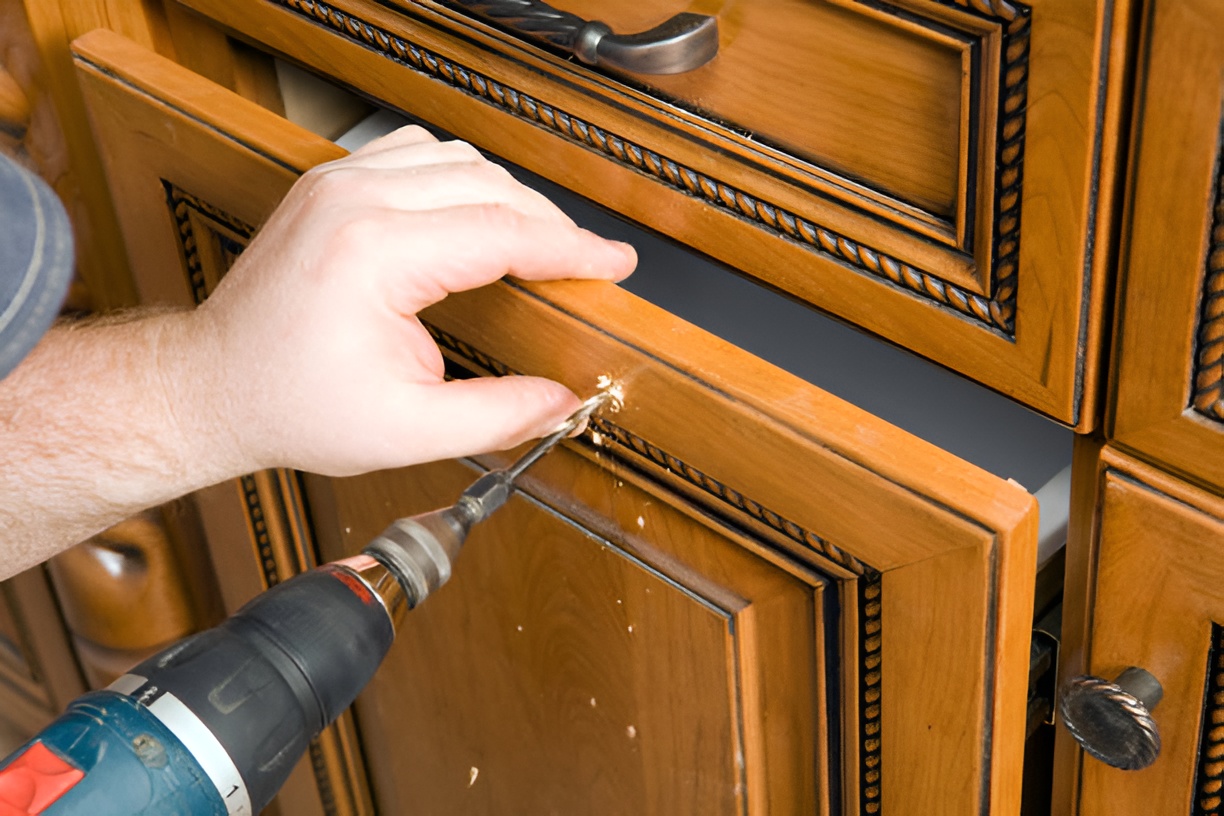 close-up of a man drilling a hole for a new kitchen drawer handle